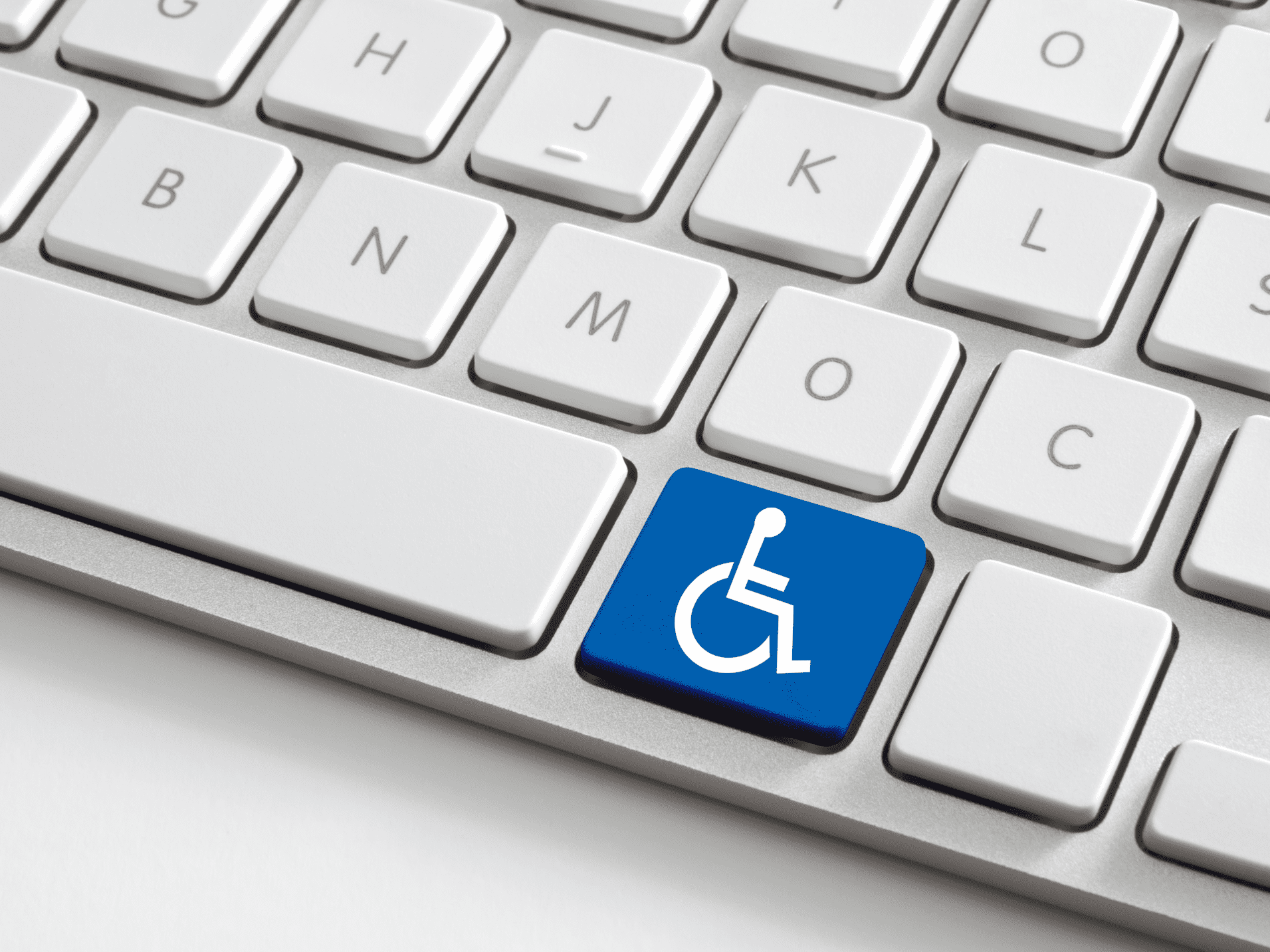 Nahaufnahme einer Computer-Tastatur mit einem blauen Behindertensymbol auf der Enter-Taste.