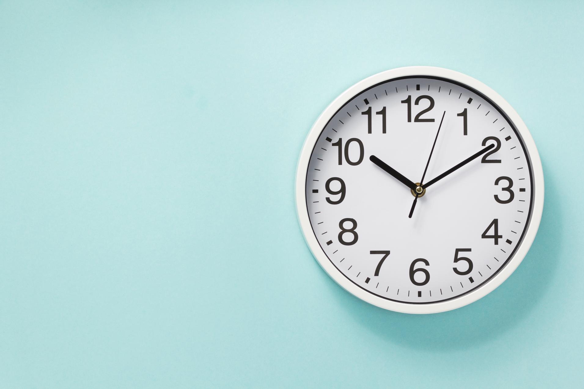 Wanduhr mit wei&szlig;en Ziffern und Zeigern an einer mintgr&uuml;nen Wand.