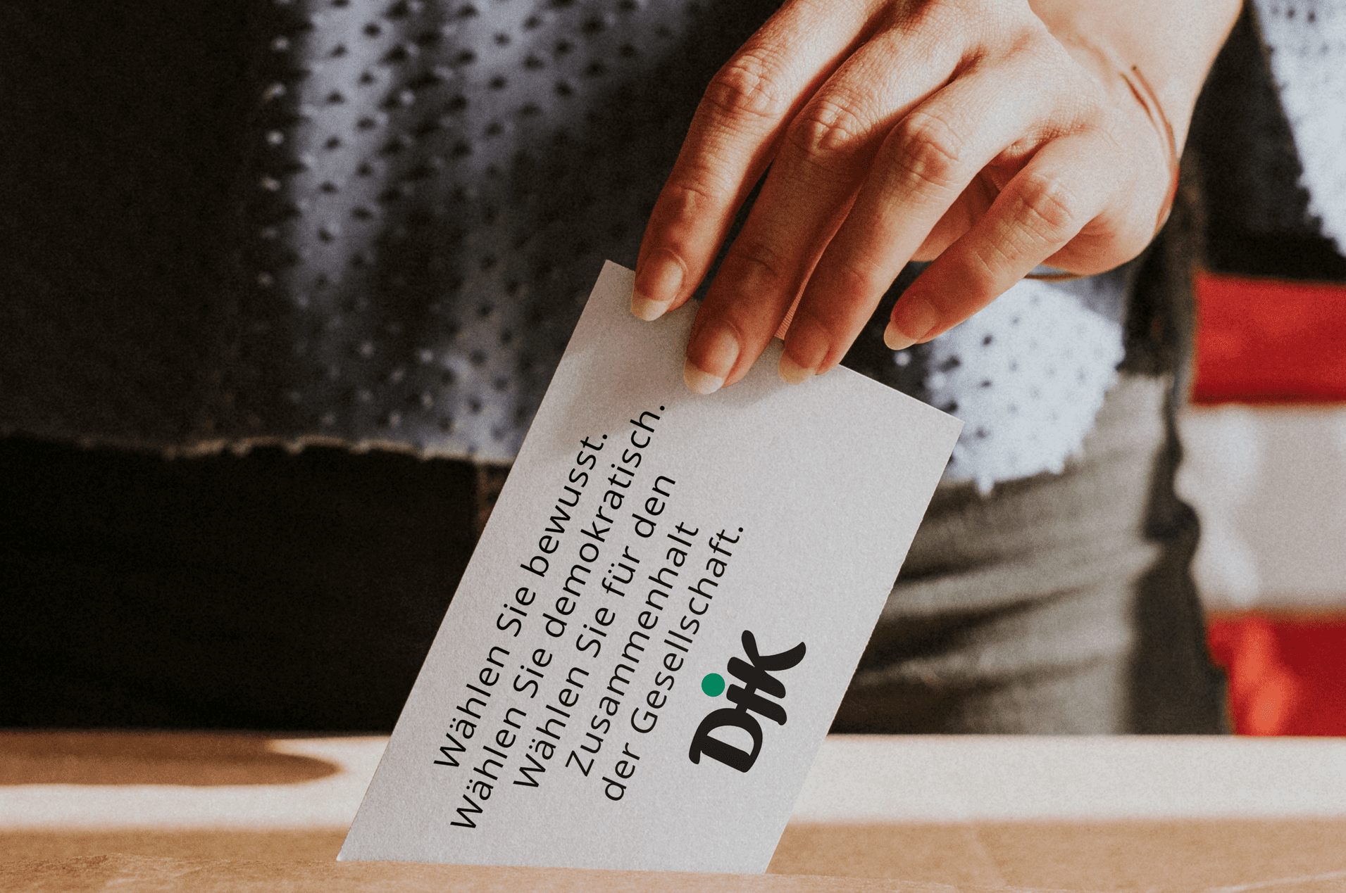 Hand einer Person, die eine Wahlkarte in eine Box einwirft, mit Text &uuml;ber bewusstes W&auml;hlen und Demokratie.