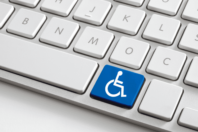 Nahaufnahme einer Computer-Tastatur mit einem blauen Behindertensymbol auf der Enter-Taste.