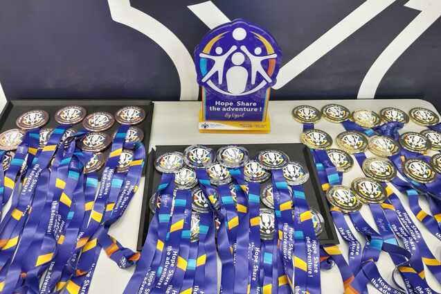 Troph&auml;en und Medaillen mit blauen B&auml;ndern auf einem Tisch vor einem einfarbigen Hintergrund.