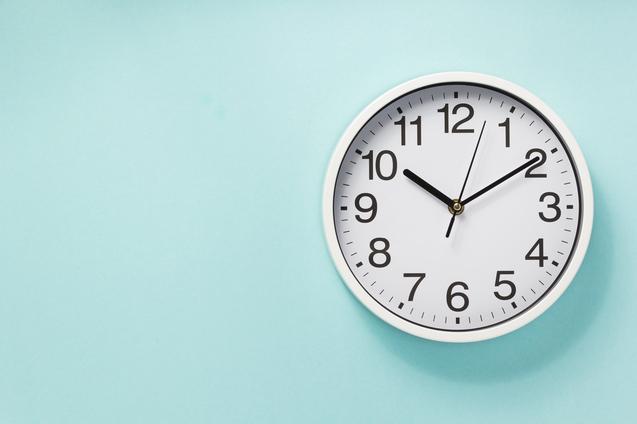 Wanduhr mit wei&szlig;en Ziffern und Zeigern an einer mintgr&uuml;nen Wand.