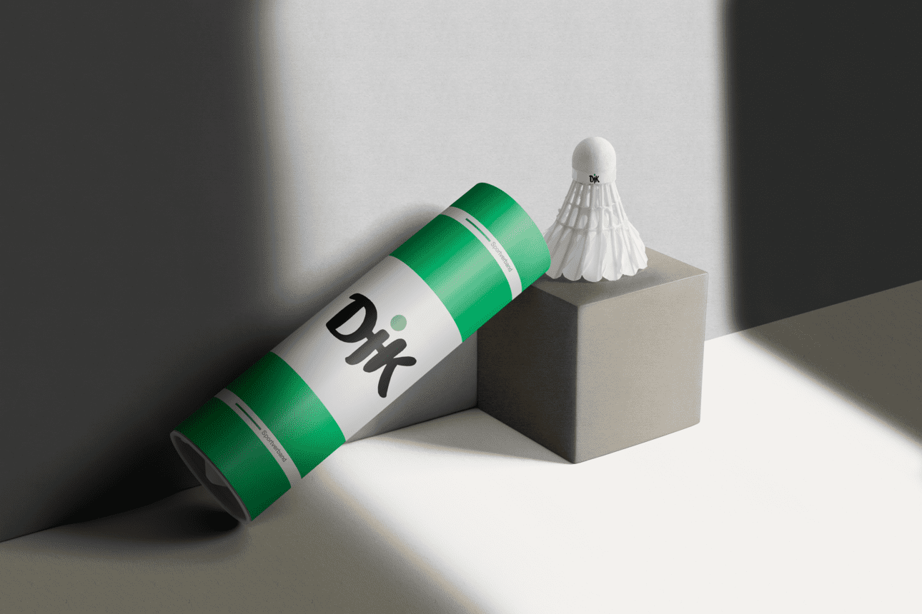 Verpackung eines Badmintonschl&auml;gers steht neben einem Badmintonball auf einem grauen Block. Licht f&auml;llt auf die Szene.