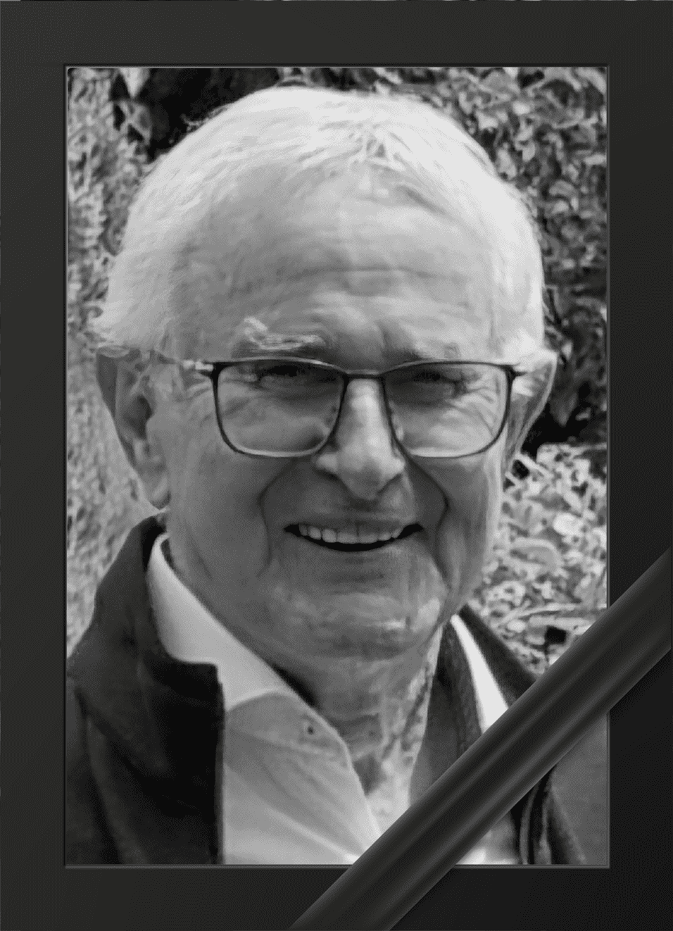 Portrait eines l&auml;chelnden &auml;lteren Mannes mit Brille, umrahmt von einem Trauerrand.