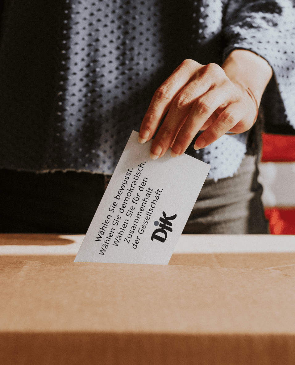 Hand einer Person, die eine Wahlkarte in eine Box einwirft, mit Text über bewusstes Wählen und Demokratie.