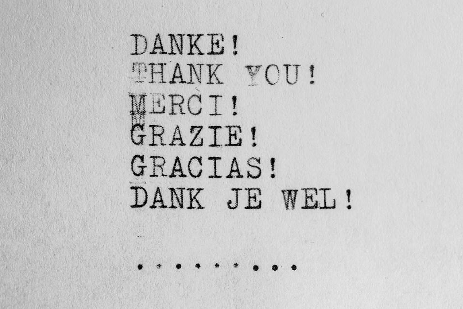 Text mit verschiedenen Sprachen f&uuml;r "Danke" auf grauem Hintergrund, typografisch gesetzt.