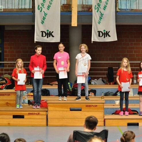 Sechs Kinder in roten T-Shirts stehen auf einer B&uuml;hne und halten Urkunden in den H&auml;nden.