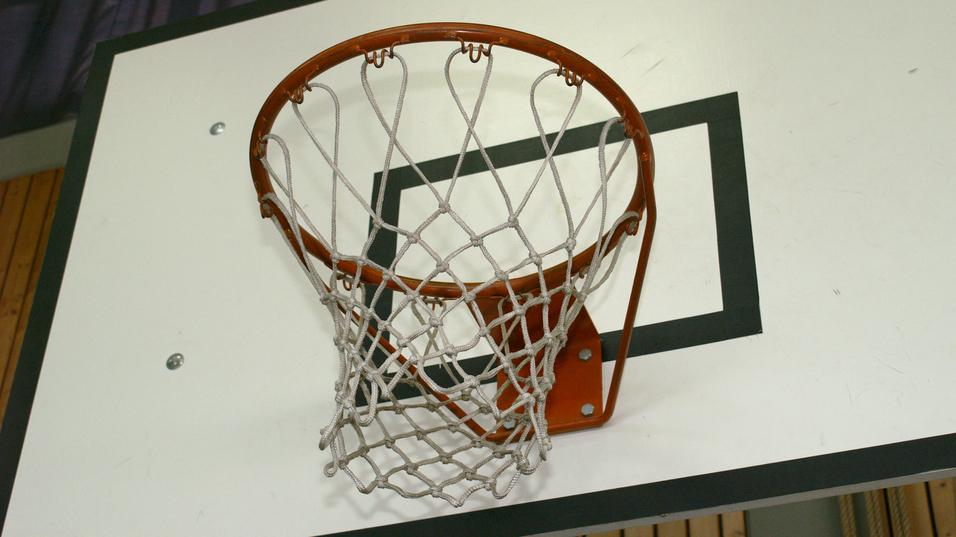 Nahaufnahme eines Basketballkorbs an einer Wand mit schwarzem Rechteck und Netz.