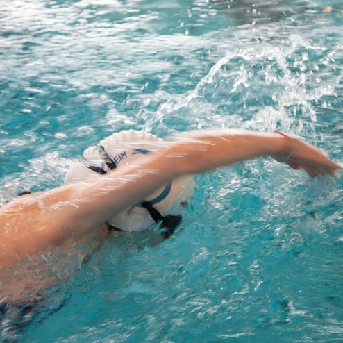 Schwimmerin in blauer Badebekleidung, die im Wasser einen Armzug ausf&uuml;hrt, Spritzwasser um den Arm herum.