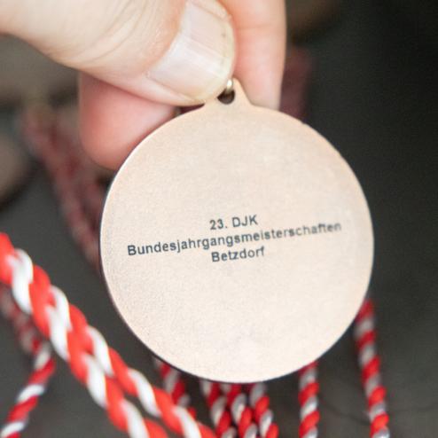Bronzene Medaille mit eingravierter Aufschrift: &bdquo;23. DJK Bundesjahrgangsmeisterschaften Betzdorf&ldquo;, gehalten in einer Hand.