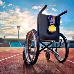 Rollstuhl mit Goldmedaille steht auf einer Laufbahn im Stadion, im Hintergrund der Himmel mit Wolken.