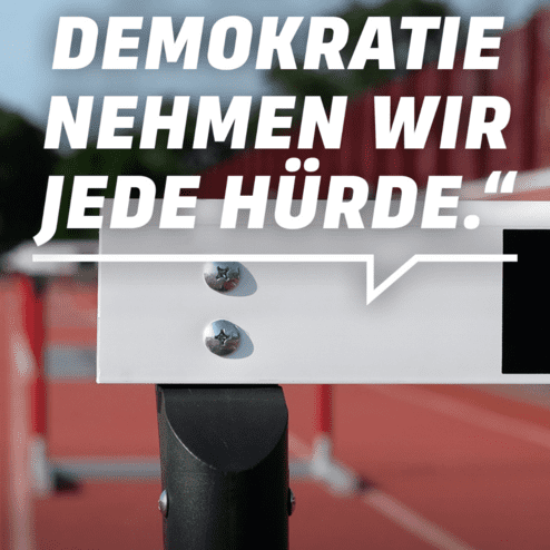 Nahaufnahme einer H&uuml;rde auf einem Sportplatz, mit dem Schriftzug zur Unterst&uuml;tzung demokratischer Werte.