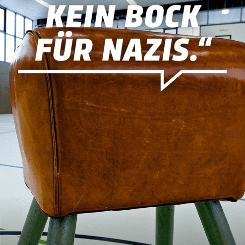Lederne Sportbank in einem Hallenbereich mit dem Schriftzug &bdquo;Mein Motto: Kein Bock f&uuml;r Nazis.&ldquo; im Vordergrund.