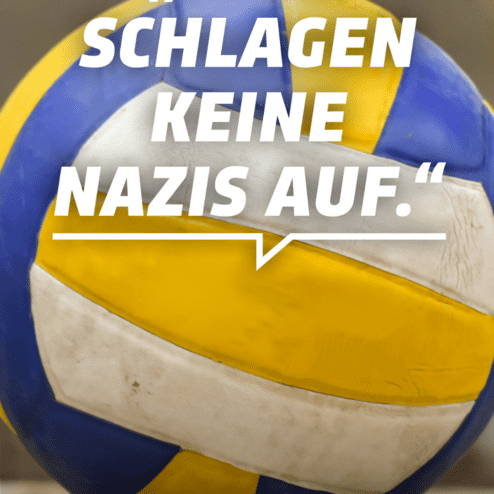 Nahaufnahme eines Volleyballs mit der Aufschrift &bdquo;Hier schlagen keine Nazis auf&ldquo; auf unscharfem Hintergrund.