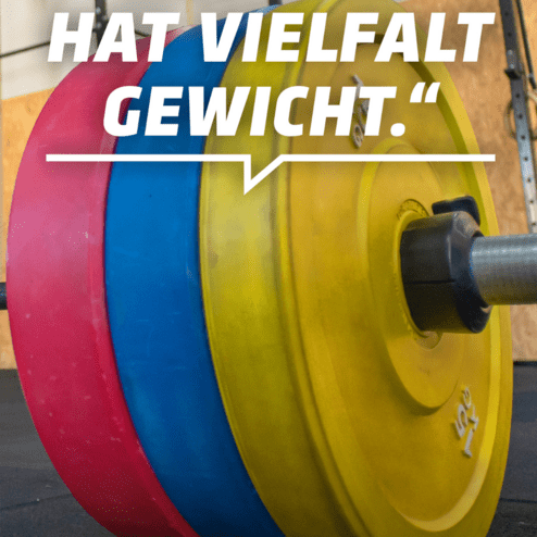 Nahaufnahme von Gewichtsscheiben in verschiedenen Farben auf einer Hantelstange, mit motivierendem Text im Hintergrund.