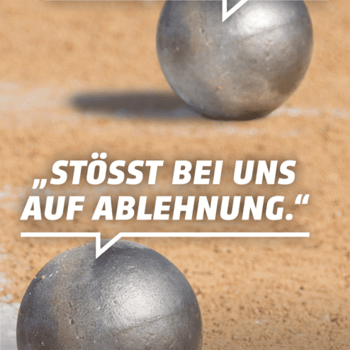 Zwei silberne Kugeln auf einer Sandfl&auml;che, umgeben von einem Zitat gegen Fremdenhass und f&uuml;r demokratische Werte.