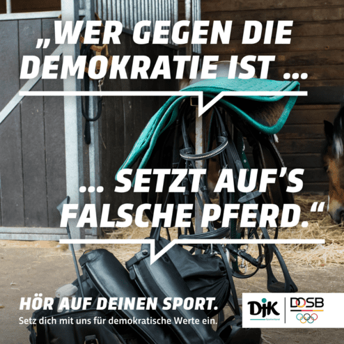 Sattel und Stiefel stehen vor einer Pferdebox, das Zitat &uuml;ber Demokratie ist prominent im Bild platziert.