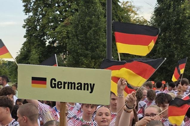 Gruppe junger Menschen mit Deutschlandfahnen, eine Person h&auml;lt ein Schild mit &bdquo;Germany&ldquo; und alle tragen einheitliche T-Shirts.