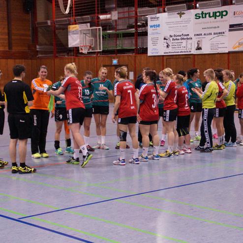 Zwei Handballteams stehen sich in einer Halle gegen&uuml;ber und sch&uuml;tteln sich die H&auml;nde vor dem Spielbeginn.