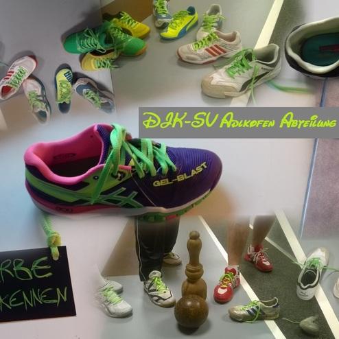 Verschiedene Sport- und Turnschuhe auf einem Tisch, darunter eine gro&szlig;e Schuhgruppe mit bunten Schn&uuml;rsenkeln.