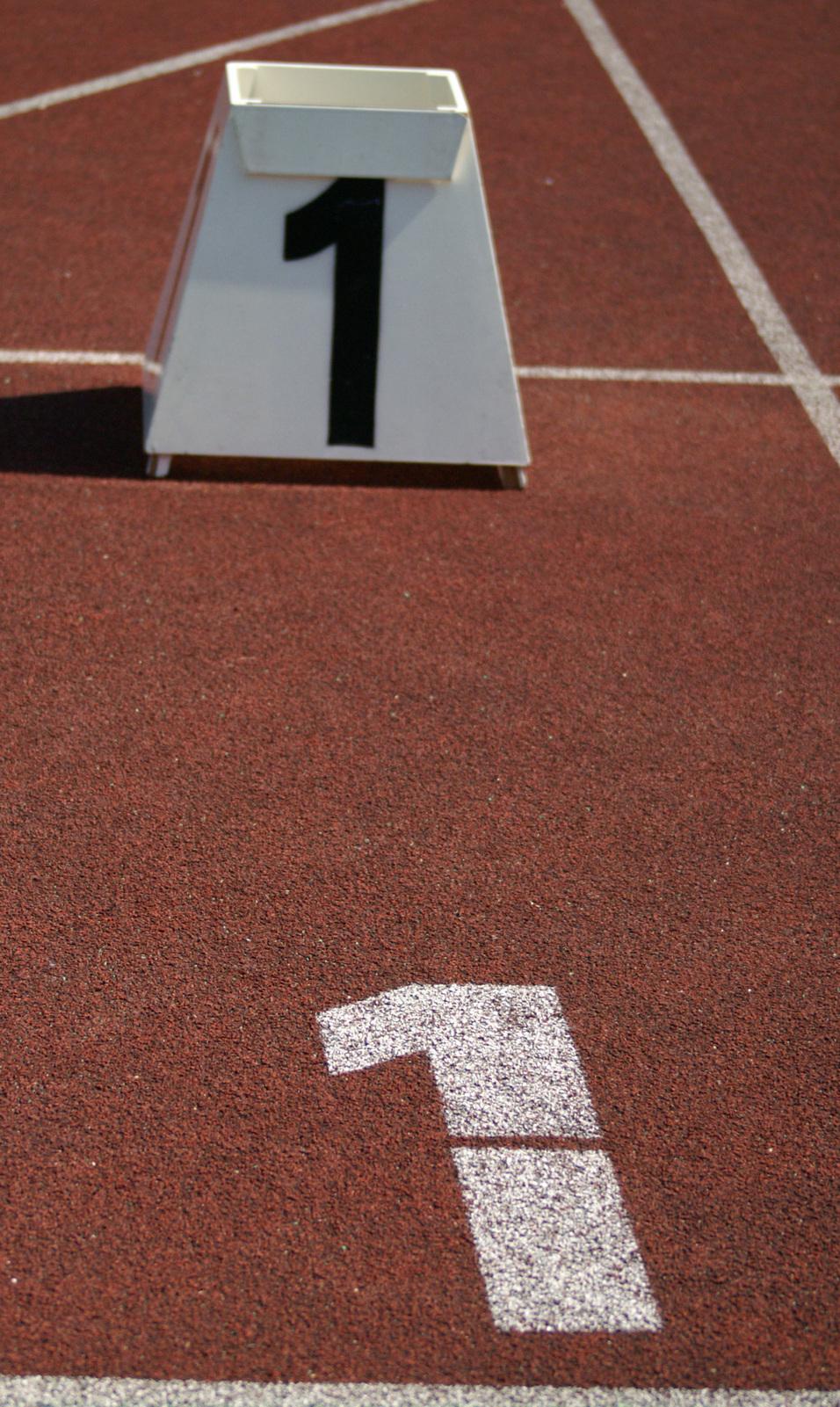 Block mit der Startnummer 1 auf einem roten Laufbahn-Untergrund mit wei&szlig;er Markierung der gleichen Zahl.