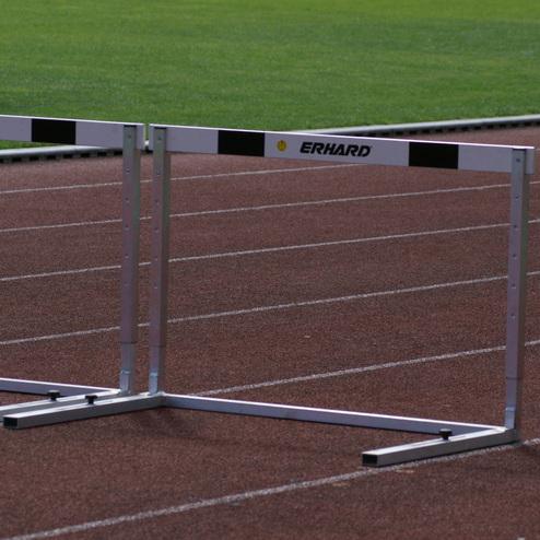 H&uuml;rden auf einer Laufbahn mit gr&uuml;ner Rasenfl&auml;che im Hintergrund. Die H&uuml;rden sind markiert und stabil aufgestellt.