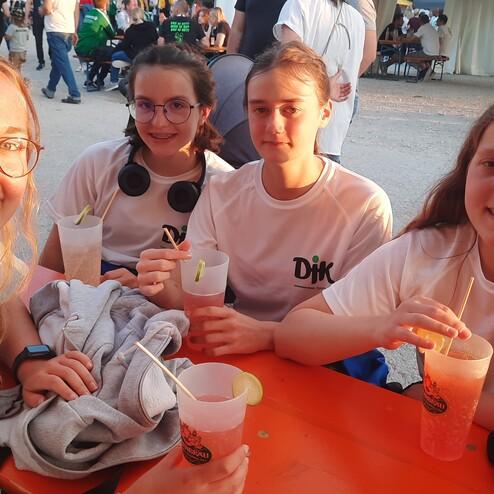 Vier Jugendliche in wei&szlig;en T-Shirts sitzen an einem Tisch und trinken Cocktails aus Bechern.