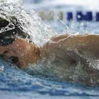 Ein Junge schwimmt mit Schnorchel und Schwimmbrille im Wasser, spritzende Wassertropfen um ihn herum.