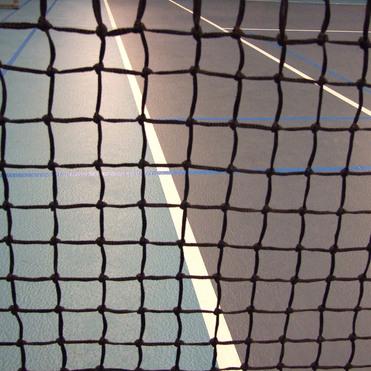 Blick durch ein Tischtennisnetz auf die markierten Linien einer Tischtennisplatte.