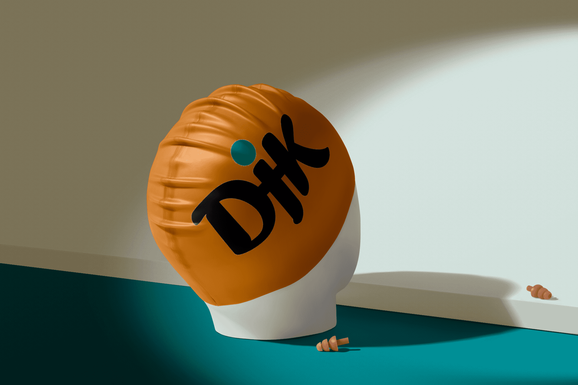 Schwimmkappe mit dem Aufdruck &bdquo;Dik&ldquo; auf einem Kopfmodell vor einer Wand, mit zwei kleinen Muscheln auf dem Boden.