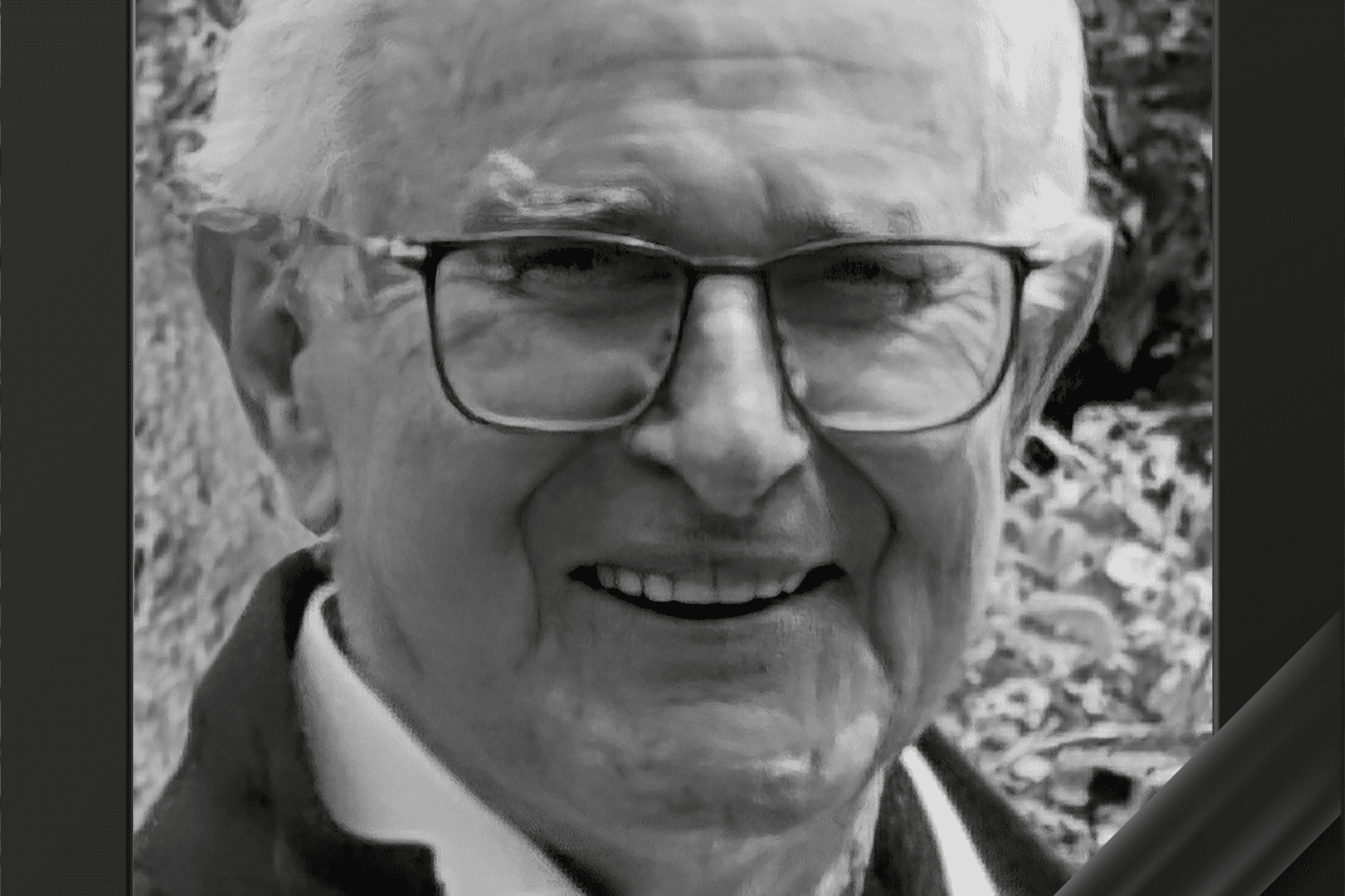 Portrait eines l&auml;chelnden &auml;lteren Mannes mit Brille, umrahmt von einem Trauerrand.