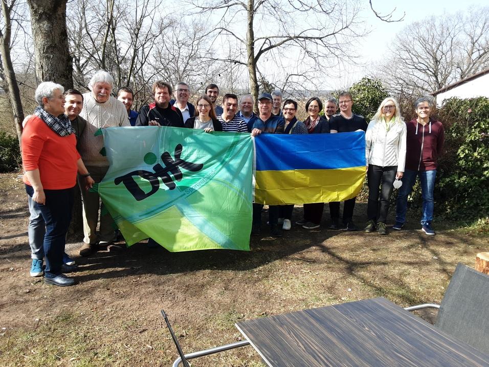 Gruppe von Menschen im Freien h&auml;lt eine gr&uuml;ne Flagge mit dem Logo "DHF" und eine ukrainische Flagge.