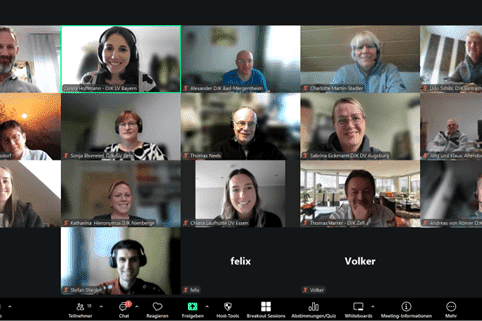 Videokonferenz mit 16 Teilnehmern, die in 4 Reihen auf Zoom-&auml;hnlicher Plattform angeordnet sind, teils am Arbeitsplatz.