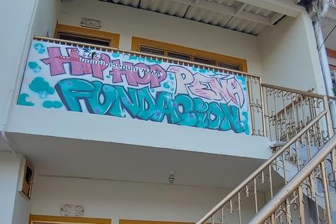 Fassade eines Hauses mit vergoldetem Gel&auml;nder und buntem Graffiti auf dem Balkon.