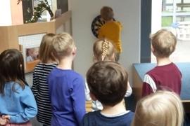 Gruppe von Kindern beobachtet einen Jungen, der eine Dartscheibe in einem hellen Raum anvisiert.