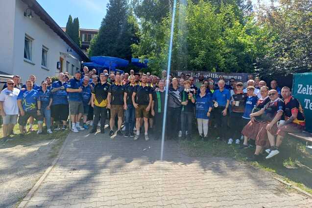 Gruppierung von Menschen in blauem und schwarzem Shirt, versammelt auf einem Weg im Freien, um einen Anlass zu feiern.