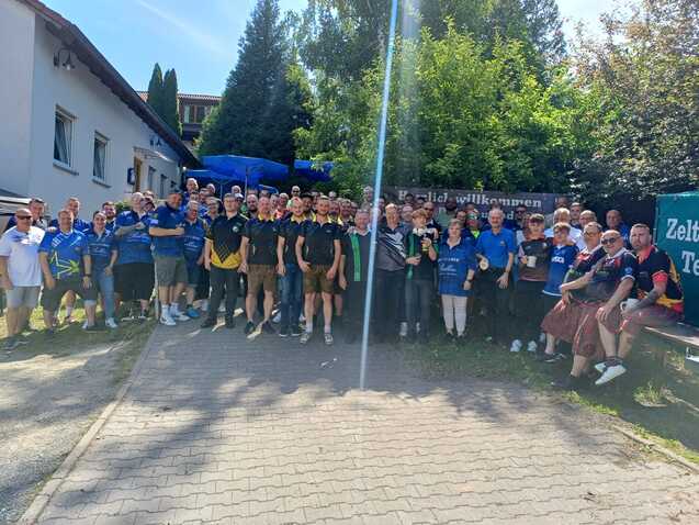 Gruppierung von Menschen in blauem und schwarzem Shirt, versammelt auf einem Weg im Freien, um einen Anlass zu feiern.
