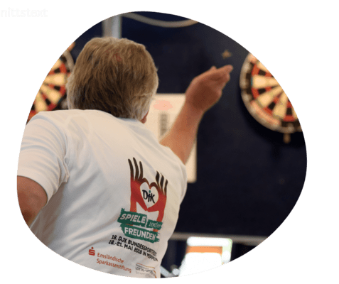 Person wirft einen Dartpfeil auf eine Dartscheibe in einem Sportveranstaltungskontext.