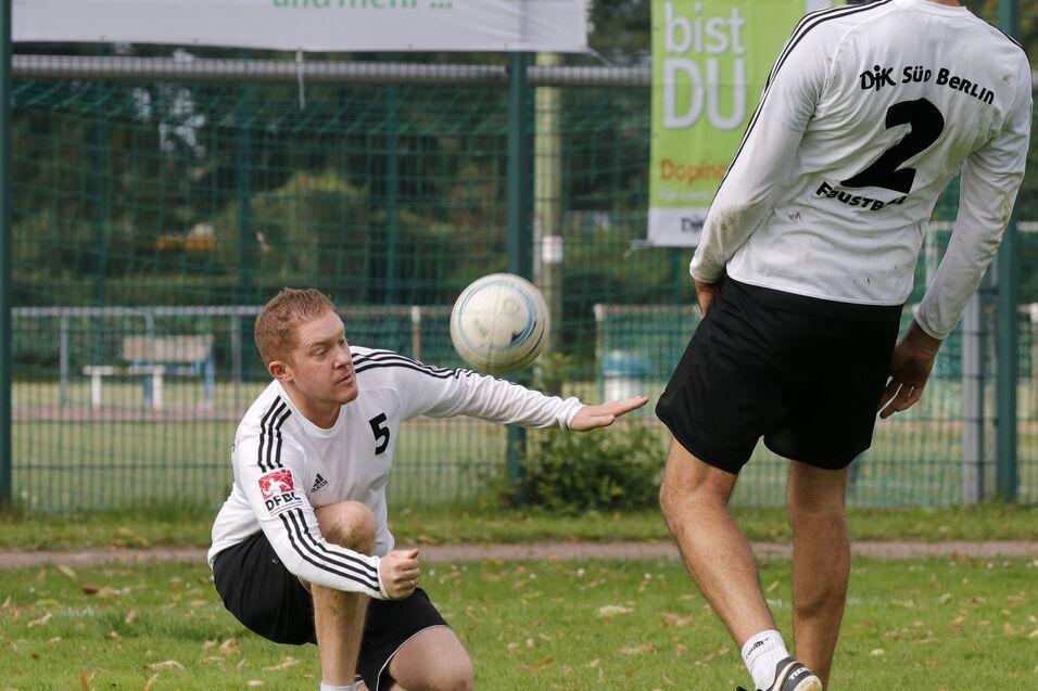 Zwei Fu&szlig;ballspieler trainieren im Freien; ein Spieler kniet, der andere passt den Ball.