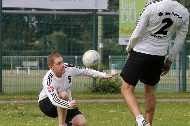 Zwei Fu&szlig;ballspieler trainieren im Freien; ein Spieler kniet, der andere passt den Ball.