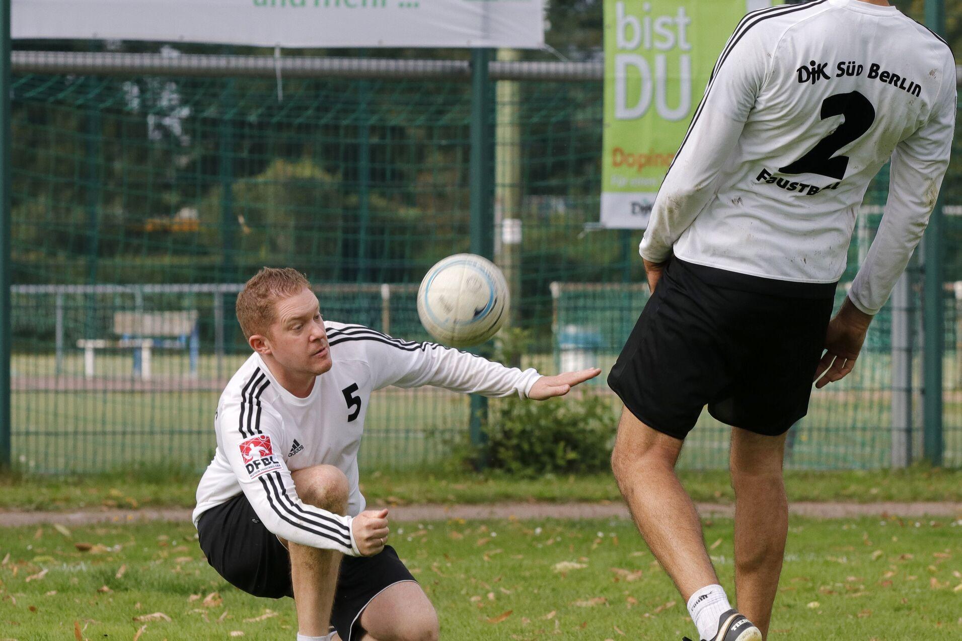 Zwei Fu&szlig;ballspieler trainieren im Freien; ein Spieler kniet, der andere passt den Ball.