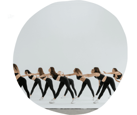 Gruppentanz von Frauen in enger Formation, schwarze Sportbekleidung, vor hellem Hintergrund.