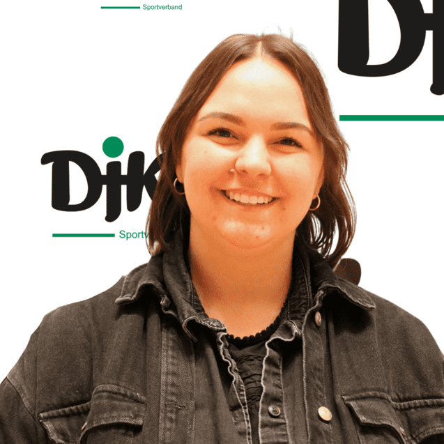 L&auml;chelnde Person mit kurzer brauner Haarfrisur vor einem Logo des Sportverbands DJK.