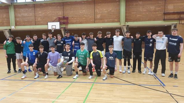 Gruppenzusammenkunft von Jugendlichen in Sportkleidung in einer Halle, einige knien, andere stehen, Handball-Atmosph&auml;re.