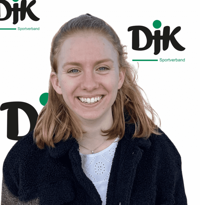 L&auml;chelnde junge Frau mit blonden Haaren, tr&auml;gt einen schwarzen Mantel, vor Hintergrund mit dem Logo "DJK Sportverband".