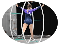 Turnerin in buntem Outfit balanciert auf einem gro&szlig;en Reifen in einer sportlichen Umgebung.