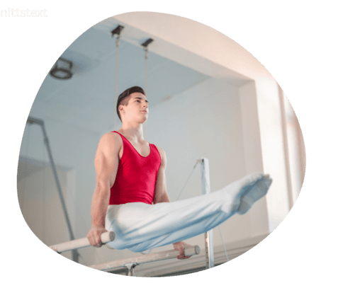 Junger Turner in rotem Trikot h&auml;lt sich an einem Barren mit gestreckten Beinen in der Luft.