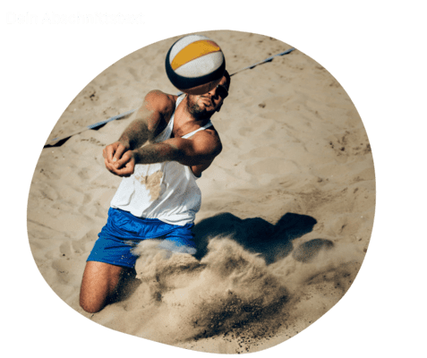 Sportler springt im Sand, um einen Volleyball in der Luft zu schlagen. Sonne und Bewegung sorgen f&uuml;r Dynamik.