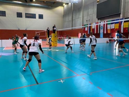 Szene eines Volleyballspiels mit Spielern in schwarzen und wei&szlig;en Trikots auf einem blauen Spielfeld.