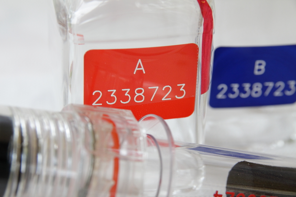 Nahaufnahme von zwei Flaschen mit roten und blauen Etiketten, die die Nummern "A 2338723" und "B 2338723" zeigen.